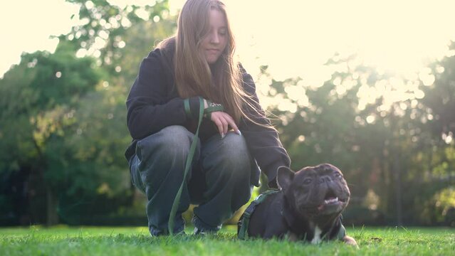 A teenage girl plays with her dog in the park