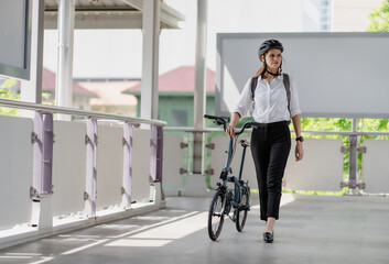 Fototapeta na wymiar Eco friendly, businesswoman ride bicycle in urban to reduce carbon footprint. Beautiful woman environment conservation person commuting with bicycling. Cycling, alternative transport for green energy.