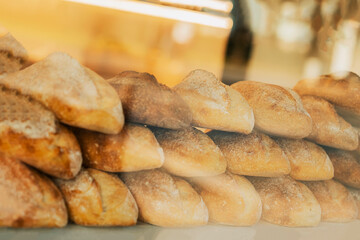 Fresh organic bread on shelves stand of shop, bakery. Freshly baked bread loaves at window of store. Street showcase