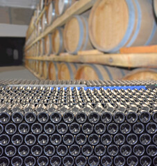 Cellar with bottles and barrels for storage of wine in winery. Making wine barrels in rows