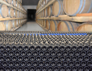 Cellar with bottles and barrels for storage of wine in winery. Making wine barrels in rows