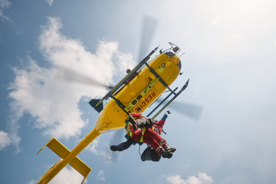 Two paramedics hanging on rope under flying helicopter emergency medical service. Themes rescue, help and heroes..