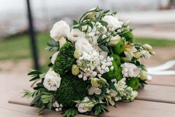 Bride's bouquet of white and green flowers on a wooden surface close-up