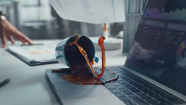 Office Manager Accidentally Spilling Hot Coffee on Working Laptop Computer with Business Presentation. Cinematic Real Slow Motion Footage with Speed Ramp Effect. Concept of Failing or Screwing Up