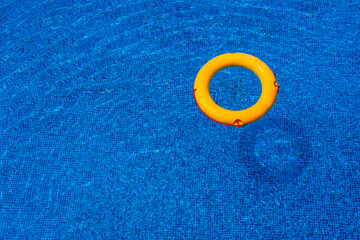 Top view of lifebuoy floating in blue swimming pool, soft focus.