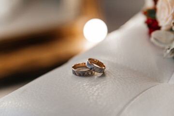 Gold wedding rings lying on a white leather chair, close-up