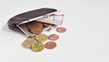An open, old wallet with small bill and euro cents on a white background.