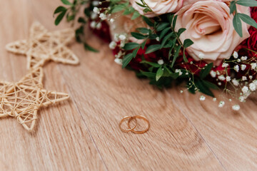 Gold wedding rings near the bride's bouquet of beige-red roses