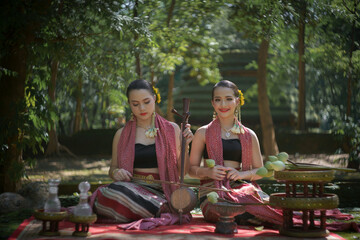 Beautiful Asian women wearing an ancient Local Thai Lanna Traditional dress costume in the old temple are happy with green natural moss in the local country of Chiang Mai, Thailand.