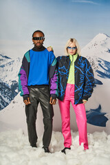 interracial couple posing in winter attire with mountain on backdrop, african american man and woman