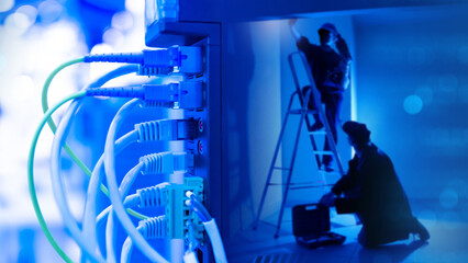 Network hardware. Men with stepladder work in dark. Fragment network equipment with wires....