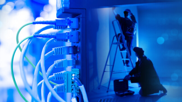 Network hardware. Men with stepladder work in dark. Fragment network equipment with wires. Installation electrical equipment. Router for internet and communications. Installation network equipment.