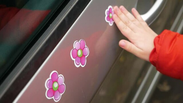 little girl puts sticker in shape of flower on car