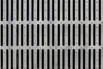 iron drainage grate with stripes, industrial object design, close-up surface texture.