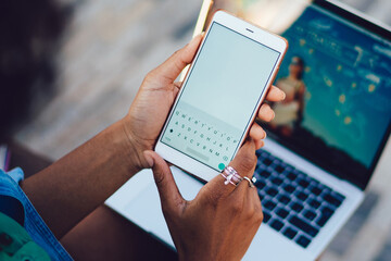 Rear close up view of female holding in hands white cellular with digital keyboard on display