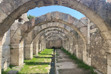 Ruins ancient city stone temple in İzmir, top arches, keystones, columns, torso statue, corridors, rooms, running fresh water between high stone wall