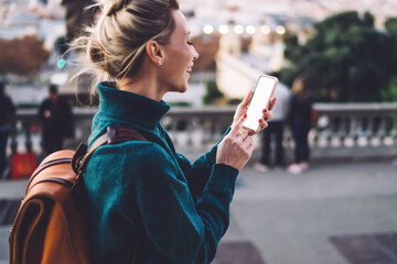 Joyful female tourist with smartphone exploring city