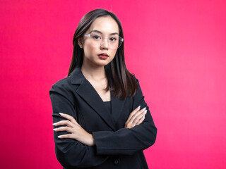 Portrait of an Asian Indonesian woman wearing a black work shirt, confidently posing with her hands folded. Isolated against a magenta background.