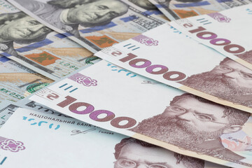 one thousand Ukrainian hrivnya banknotes lying on US dollars banknotes