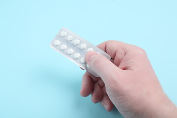 A male hand holds a package of pills. Pills blister in the hand.