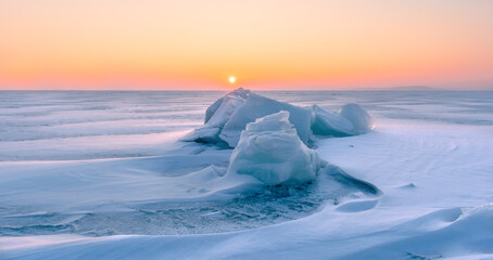 Blocks of ice on the surface of a frozen sea that is covered with snow. Frozen water surface with...
