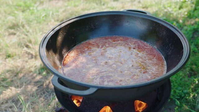 Traditional Hungarian bograch boiling on open fire. Cooking Transcarpathian dish in outdoor. Traditional Hungarian goulash in a cauldron cooked in open air. Red hot soup with meat and chili pepper. 4K