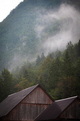 Misty mountain scenery with a wooden barn. Mist swirls over the wooden barn.