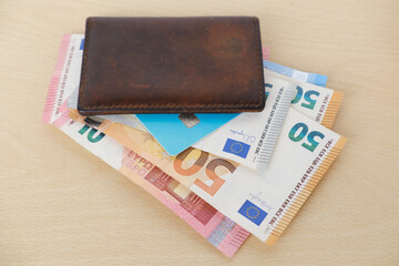 brown leather wallet with EU Currency banknotes, cash money from European Union with Bank card on wooden table, finances in business and entrepreneurship concept