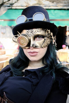 A close-up of a steampunk girl with a top hat and retro-futuristic glasses. Her gaze is intense, and her smile is mysterious.