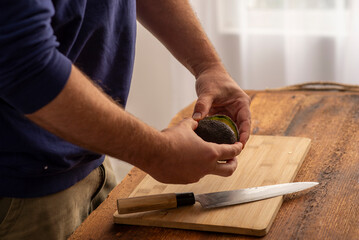 male hands holding cutting avocado on the table