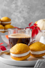 Pumpkin sandwich cookies with cream cheese on a gray concrete bsckground. Spicy autumn dessert. Copy space.