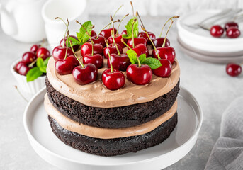 Naked Black forest cake, Schwarzwald pie. Cake with dark chocolate, cream and cherry on a gray concrete background. Copy space