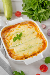Delicious zucchini lasagna with sauce bolognese in a baking dish on a white wooden bachground. Healthy food. Top view. Selective focus.