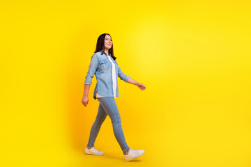 Fototapeta na wymiar Full length photo of nice person with straight hairstyle wear denim jacket pants go shopping to empty space isolated on yellow background