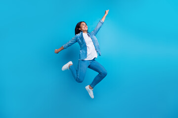 Fototapeta na wymiar Full length photo of optimistic person wear denim jacket pants flying raising fist look empty space isolated on blue color background