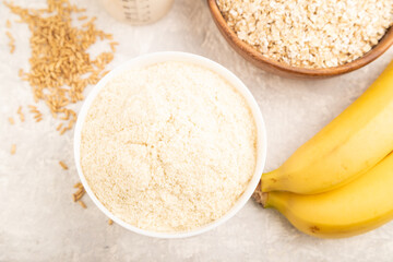 Powdered milk and oatmeal, banana baby food mix, on gray concrete, top view
