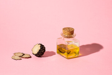 Black truffle oil on a pink background. Method for preserving truffles, aromatic oil. Season of...
