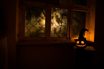 Scary Halloween pumpkin in the mystical house window at night or halloween pumpkin in night on room...