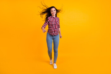 Full length photo of active optimistic person with fluttering hair wear plaid shirt jeans go...