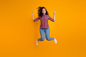 Fototapeta na wymiar Full size photo of positive woman with wavy hairdo dressed checkered shirt flying showing v-sign symbol isolated on yellow background