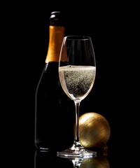 Champagne glass and bottle on a black