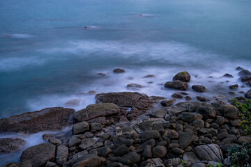 Sea waves flowing line splash over rock on the beach. Seascape before sunrise.