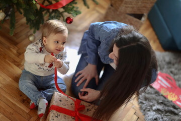 Unwrapping Christmas Joy: Nanny and Toddler's Surprise by the Christmas Tree