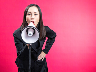 Portrait of an Asian Indonesian woman wearing a black work shirt, using a megaphone, and shouting....