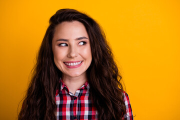 Portrait of satisfied optimistic person with curly hairstyle wear plaid shirt look at sale empty space isolated on yellow background