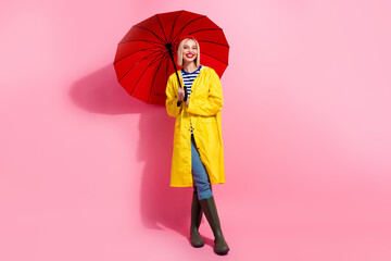 Full length photo of dreamy sweet lady wear raincoat holding umbrella walking empty space isolated...