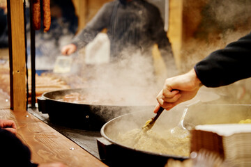 Process of cooking street food outdoors. Frying pan with fried dishes. Christmas Fair at Wroclaw...