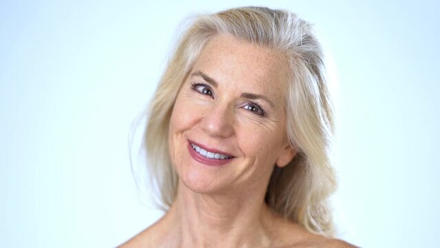 Closeup of happy smiling attractive 50s, 60s, middle aged mature woman looking at camera on white background. Anti age face beauty, skin and body care, wellness self care concept. Close up portrait.