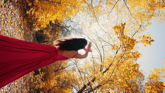 beautiful woman in a red dress poses in a bright autumn forest. vertical frame