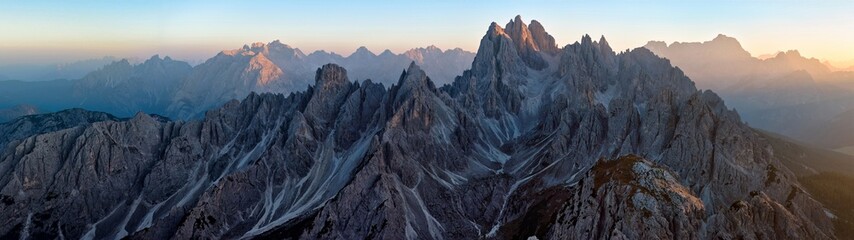 Panoramic view from Tre Cime di Lavaredo of the illuminated peaks of the Cime Eotvos mountain massif, with the three thousanders Punta Sorapis and Antelao in the background, Dolomites, Italy. 